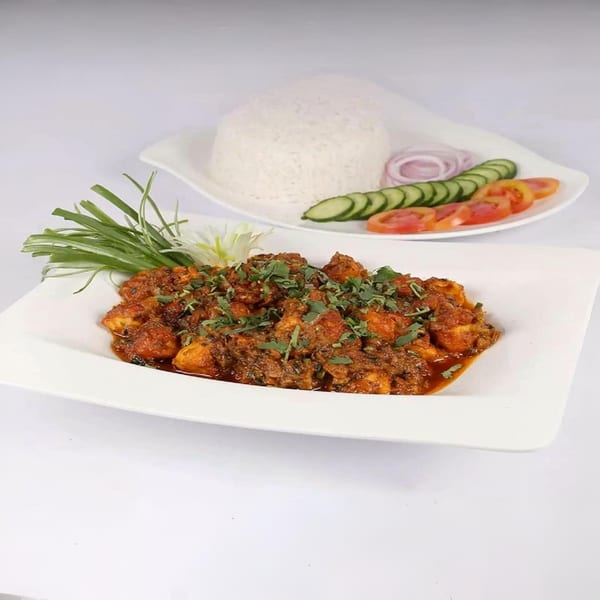 Indian chicken curry with rice and a side salad of cucumber, tomato, and onion.