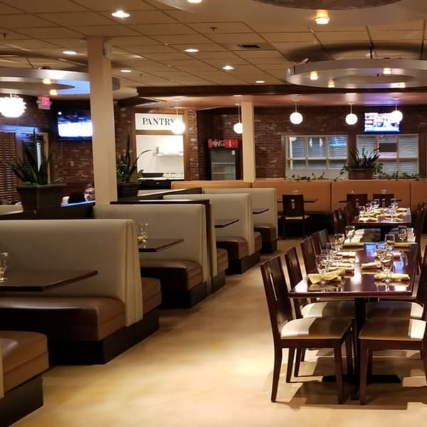 Interior of Garnish Restaurants, featuring rows of booths and dining tables set with glasses and napkins.