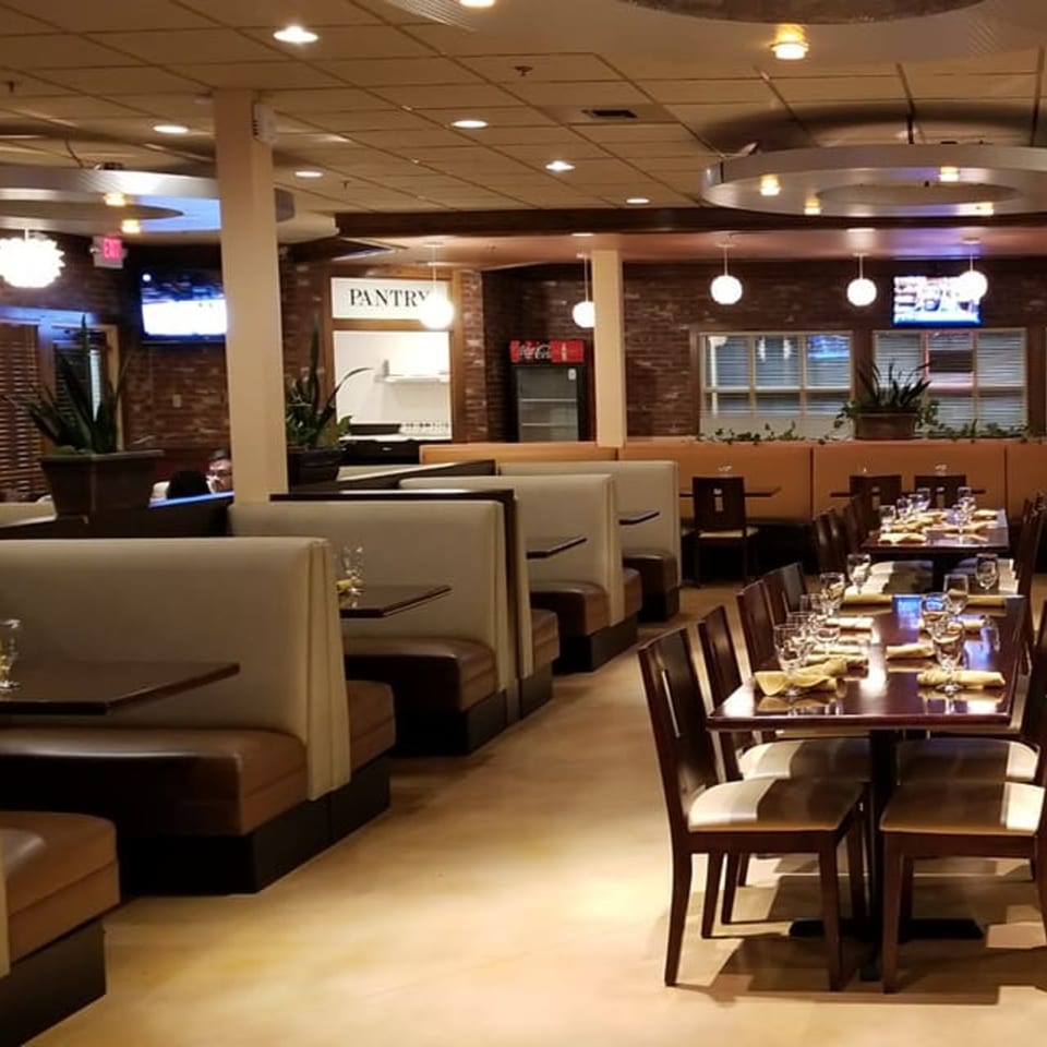 Interior of Garnish Restaurants, featuring rows of booths and dining tables set with glasses and napkins.