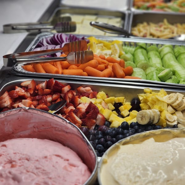 A buffet spread with fresh fruit, vegetables, and two tubs of ice cream at Garnish Restaurants.