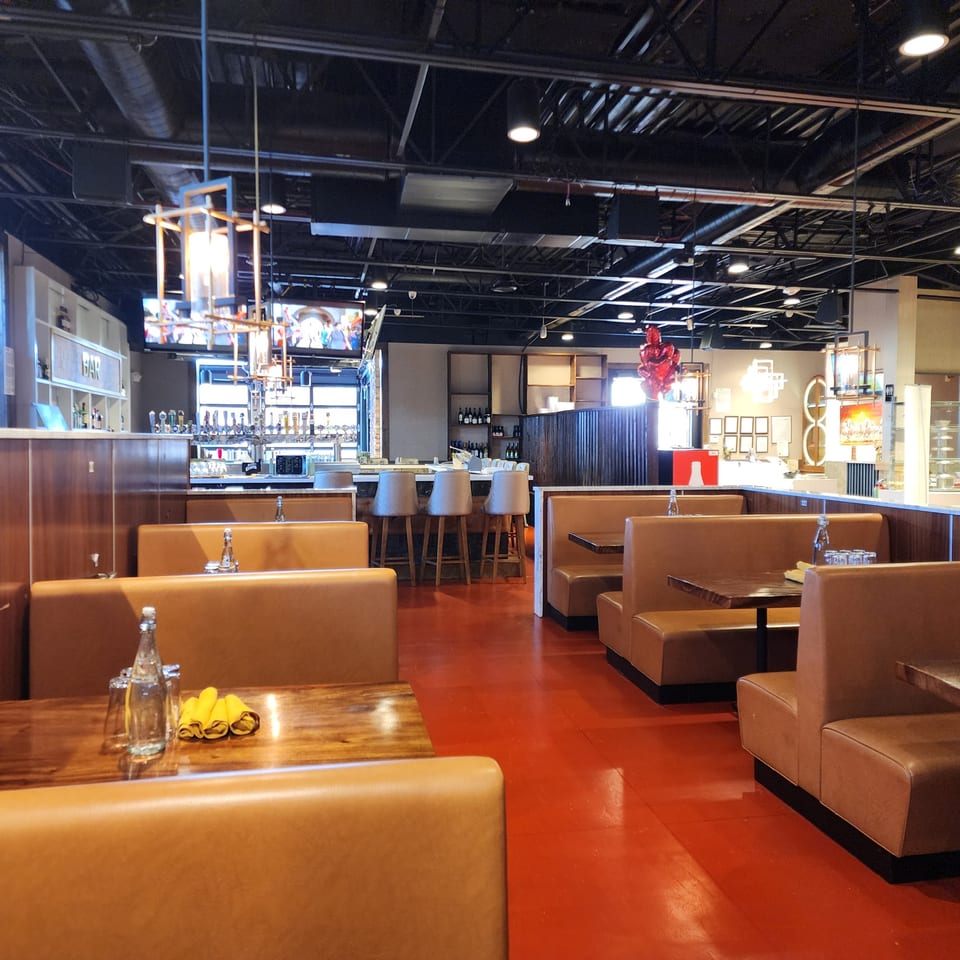 Interior of Garnish Restaurants, an Indian restaurant, with empty booths, tables, and a bar area.