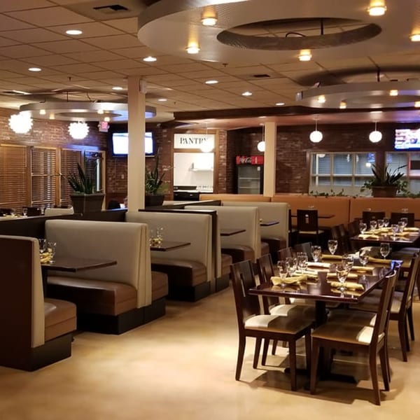 Interior of Garnish Restaurants, an Indian restaurant, with empty tables, booths, and brick walls.