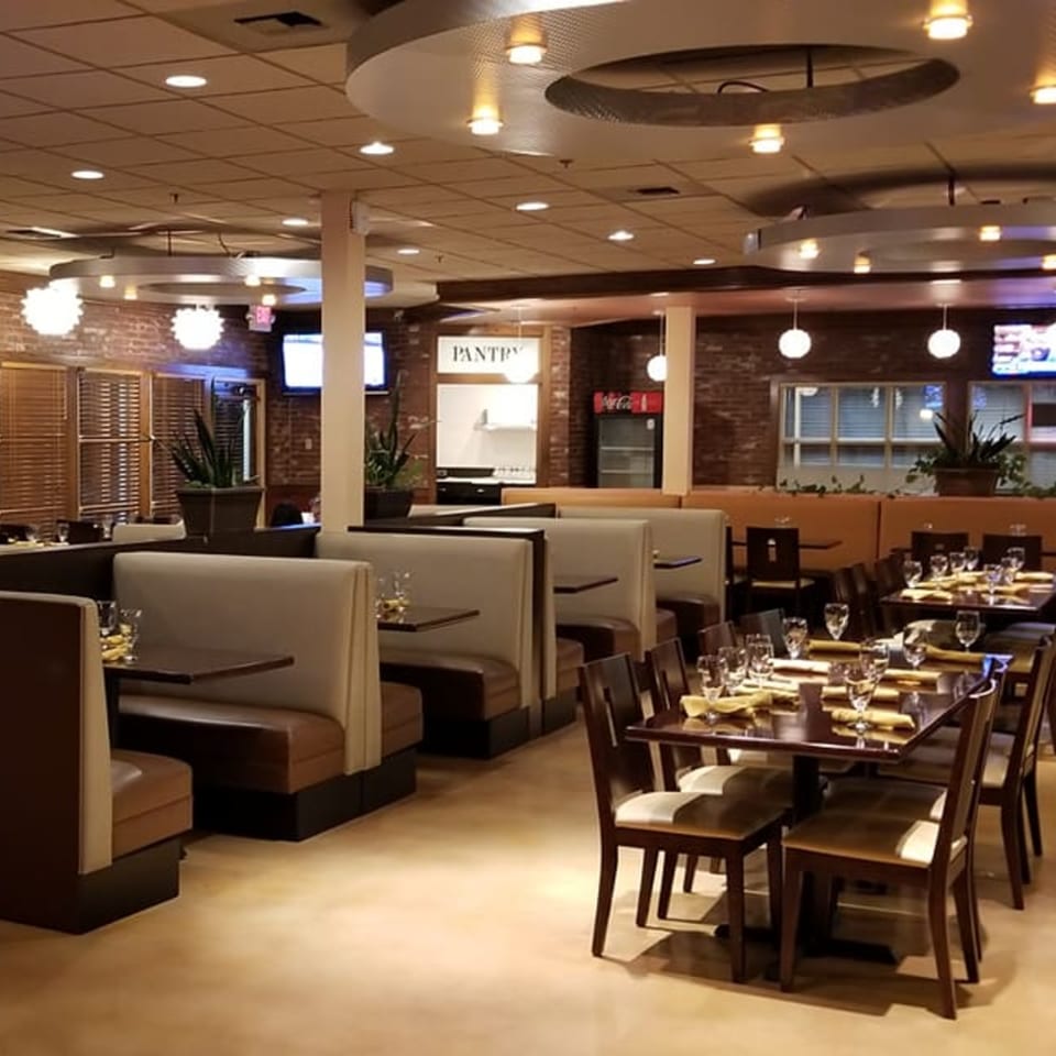Interior of Garnish Restaurants, an Indian restaurant, with empty tables, booths, and brick walls.